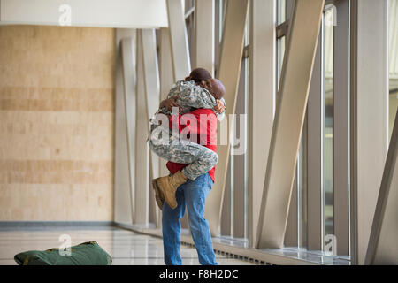 African American soldier abbracciando il marito in aeroporto Foto Stock