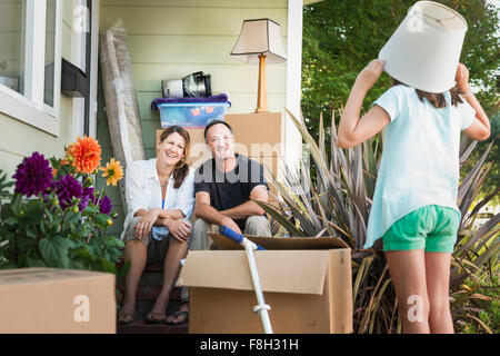 I genitori caucasici guardando la figlia giocare fuori casa Foto Stock