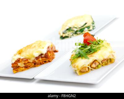 Close-up di un tradizionale lasagne fatte con carne macinata ragù alla bolognese e rabboccato con foglie di basilico servito su una piastra bianca Foto Stock