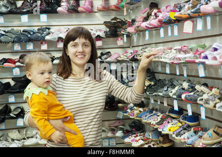 Felice madre con bambino sceglie scarpe per bambini al negozio di moda Foto stock Alamy