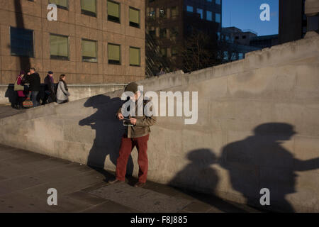 Un uomo si ferma per consultare una mappa sul lato sud del Ponte di Londra a Southwark, Londra centrale Foto Stock