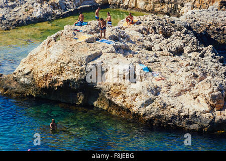 I turisti sulla roccia sopra l'oceano Polignano Puglia Puglia Italia Europa Foto Stock