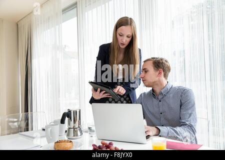 Giovane donna che mostra collega digitale compressa a colazione business meeting Foto Stock