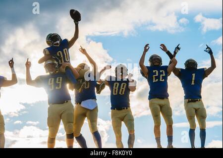 Gruppo di giovani american football giocatori, celebrando Foto Stock