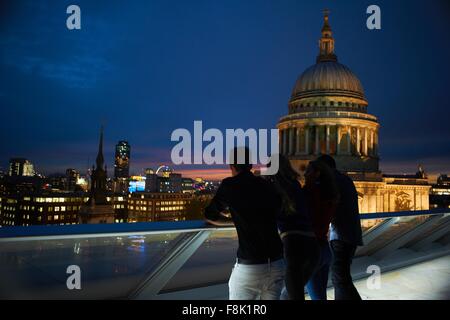 Stagliano vista posteriore di due giovani coppie che guarda a St Pauls di notte, Londra, Regno Unito Foto Stock