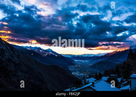 Vista distanti su strade coperte di neve tetti al tramonto, la Valtellina, Italia Foto Stock