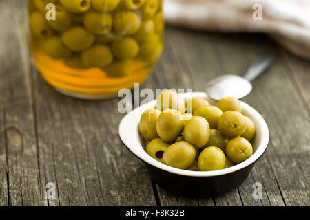 Olive verdi snocciolate in ciotola sul tavolo di legno Foto Stock