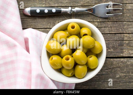 Olive verdi snocciolate in ciotola sul tavolo di legno Foto Stock