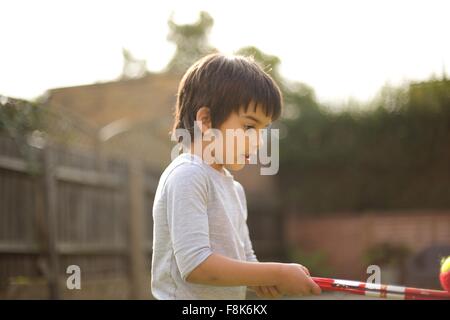 Vista laterale del boy holding bilanciamento del giocattolo palla da tennis Foto Stock