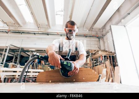 Uomo di skateboard di levigatura in officina Foto Stock