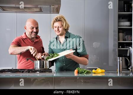 Voce maschile giovane preparare il cibo insieme in cucina Foto Stock