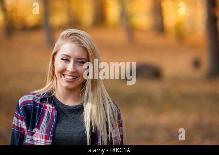 Testa e la spalla Ritratto di giovane donna con capelli lunghi biondi nella foresta di autunno Foto Stock