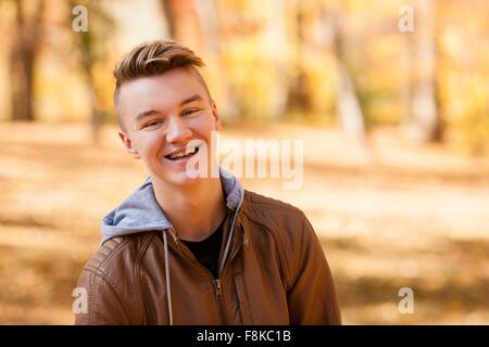 Testa e la spalla ritratto di ragazzo adolescente indossando giacca di pelle nella foresta di autunno Foto Stock