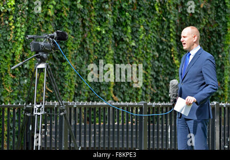 Londra, Inghilterra, Regno Unito. Reporter facendo un notizie in diretta relazione con una sola mano - College Green di fronte alla Casa del Parlamento Foto Stock