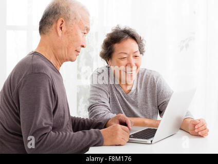 Felice coppia Senior utilizzando laptop in salotto Foto Stock