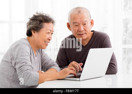 Felice coppia Senior utilizzando laptop in salotto Foto Stock