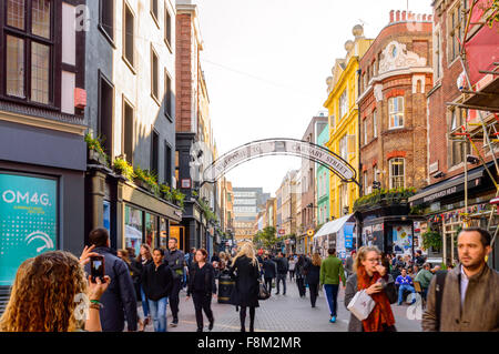 Una ragazza di prendere una foto dello smartphone di Carnaby Street cercando molto trafficata piena di acquirenti. Foto Stock