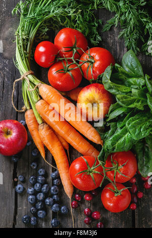 Assortimento di frutta fresca, verdura e bacche di carote, spinaci, i pomodori, le mele rosse, mirtilli e mirtilli rossi sopra il vecchio w Foto Stock