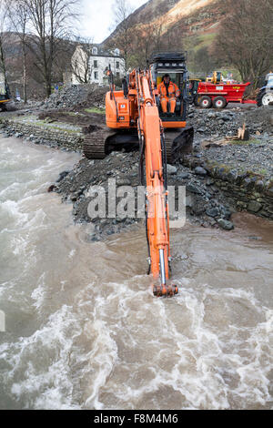 Glenridding, Cumbria, 10 dicembre 2015. Regno Unito Meteo. Dopo la pioggia caduta nella notte ha causato ulteriori inondazioni come il fiume che scorre attraverso il villaggio di nuovo in overflow. Con i servizi di soccorso sono stati chiamati in ultima notte per aiutare le persone a sicurezza come persone di possedimenti decorazioni natalizie sono state lavate in fondo alla strada. Scavatori sono state utilizzate questa mattina per cercare e dragare i detriti dal fiume nel tentativo di evitare ulteriori inondazioni. Nella vicina Patterdale la prova della potenza dell'acqua dalla tempesta Desmond potrebbe anche essere visto dove alluvione aveva scoppiare attraverso la superficie della strada. Credito: David Forster/Alamy Live ne Foto Stock