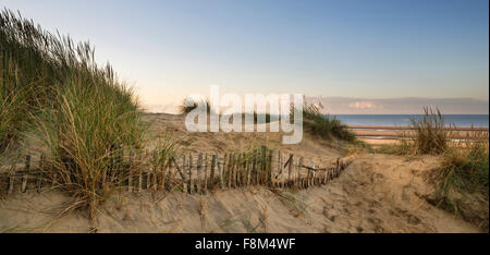 Sunrise oltre le dune di sabbia sul sistema giallo sabbia spiaggia dorata Foto Stock