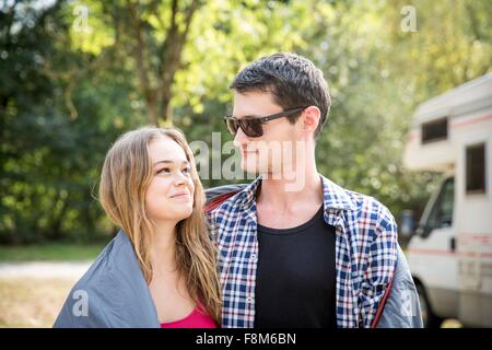 Coppia giovane avvolto in una coperta e all'aperto, faccia a faccia sorridente Foto Stock