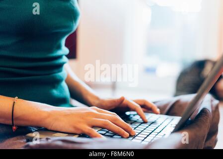 Tagliate a metà la sezione di metà donna adulta digitazione sul computer portatile Foto Stock