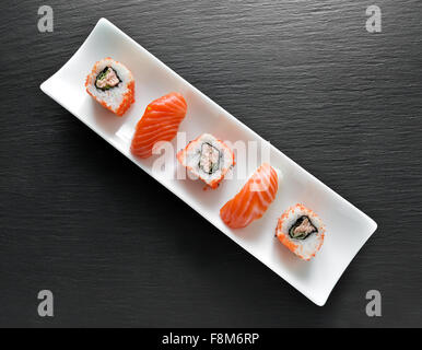 Il Sushi e rotoli su un bianco rettangolare piatto e tavola di ardesia Foto Stock
