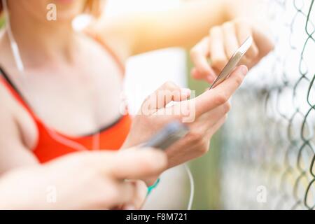 Giovani donne utilizza lo smartphone a fianco di recinzione Foto Stock