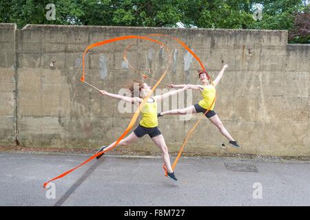 Giovani donne praticano danza a nastro su corte Foto Stock