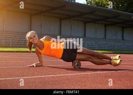 Ritratto di giovane donna runner equilibratura su lato a Race Track Foto Stock