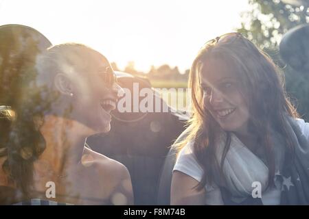 Due giovani amici di sesso femminile in chat con autovettura convertibile Foto Stock