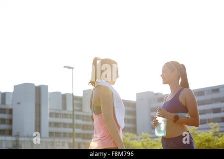 Due giovani donne in chat sul tetto urbano Foto Stock