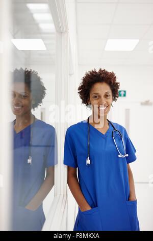 Medico appoggiata contro il vetro della finestra in ospedale Foto Stock