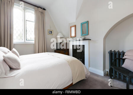 Il Grade ii Listed Country Lodge a Weybridge. Camera da letto con periodo camino. Un design contemporaneo con mobili moderni e pareti bianche. Foto Stock