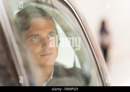 Imprenditore guardando fuori della finestra auto Foto Stock