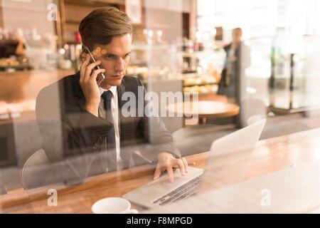 Imprenditore lavorando sul computer portatile in cafe Foto Stock