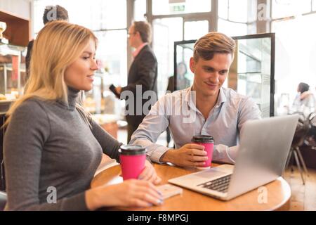 Imprenditore e imprenditrice utilizzando laptop in cafe Foto Stock