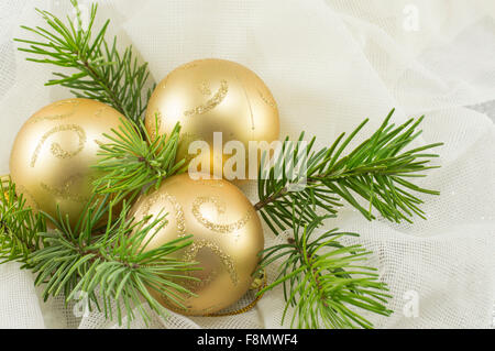 Dorata Ornamenti natale su un abete del ramo Foto Stock