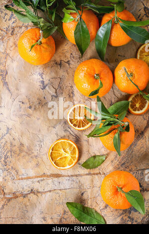 Tangerini con foglie e secchi tagliati a fettine di arancio marrone sulla superficie di pietra. Foto Stock