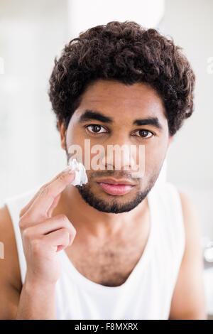 Uomo serio mettendo di schiuma da barba sul suo volto Foto Stock