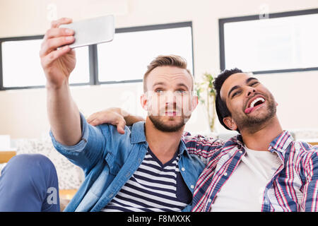 Coppia gay rilassante sul lettino tenendo selfie Foto Stock