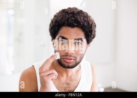 Uomo serio mettendo di schiuma da barba sul suo volto Foto Stock