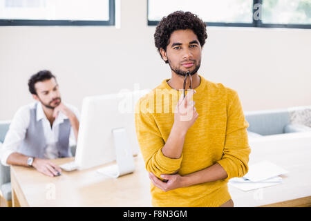 Ritratto di uomo sorridente appoggiato sulla scrivania in ufficio Foto Stock