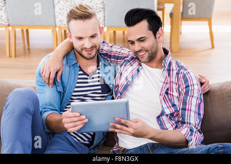 Coppia gay rilassante sul lettino usando tablet Foto Stock