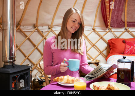 Donna gustando la prima colazione mentre il campeggio In yurta tradizionali Foto Stock