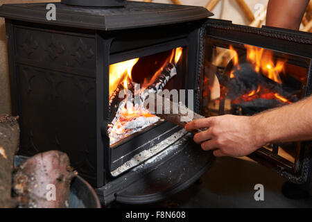 Uomo registro mettendo su stufa a legna Foto Stock