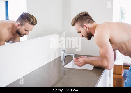 Lavaggio uomo il suo volto nel lavandino Foto Stock