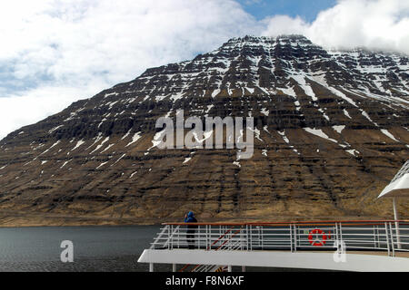 L'uomo sul ponte di una nave da crociera di guardare attraverso il binocolo Eskifjörður Islanda Foto Stock