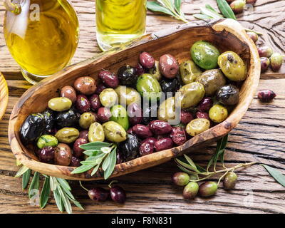 Tutta le olive da tavola nella ciotola di legno sul tavolo. Foto Stock