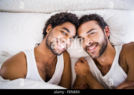 Sorridente coppia gay sul letto Foto Stock